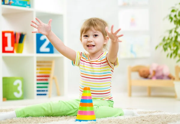 Веселая девочка ребенка, играющая в детской комнате — стоковое фото