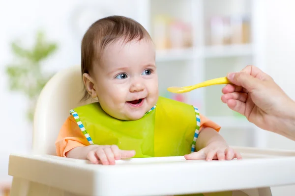 Ребенок ест здоровую пищу, сидя в кресле Хич в кухне — стоковое фото