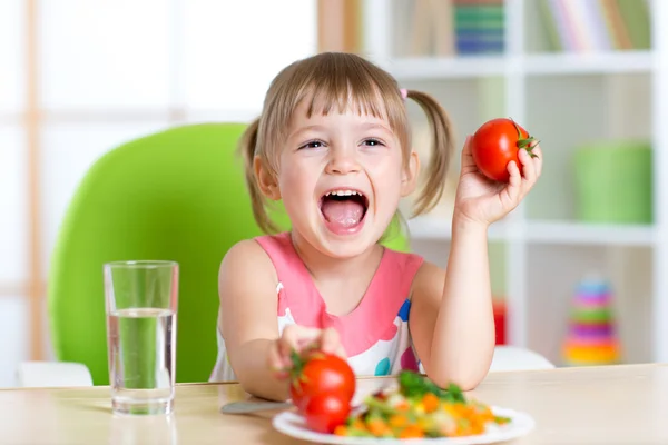 Счастливый ребенок ест обед и показывает помидоры — стоковое фото