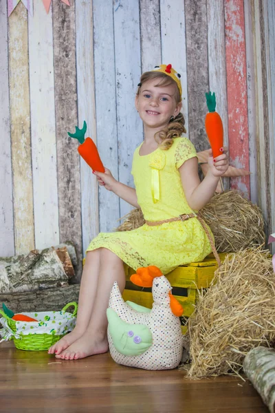 Красивая девушка в желтом платье, играя с морковью — стоковое фото
