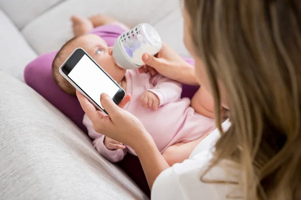 Мать, использование телефона во время кормления ребенка — стоковое фото