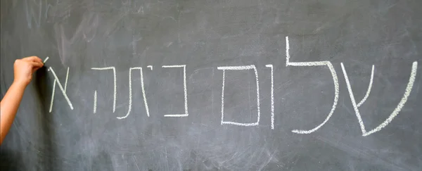 Маленький ребенок рука пишет первый класс Hello приветствия на иврите — стоковое фото