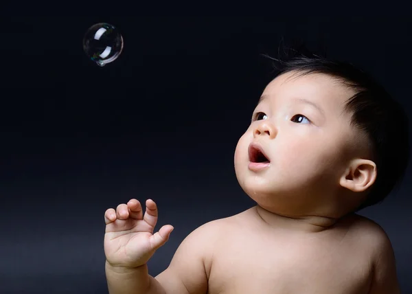 Маленький ребенок азиатских мальчик слюни и глядя мыльный пузырь — стоковое фото