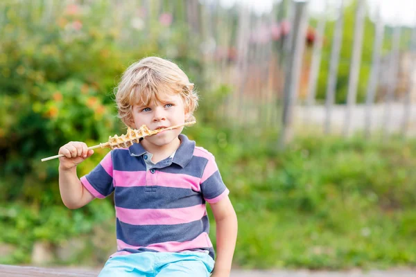Милый белокурый малыш мальчик ест вафли на соломе — стоковое фото