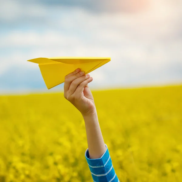 Бумажный самолетик в детей руки на желтом фоне и синий s — стоковое фото