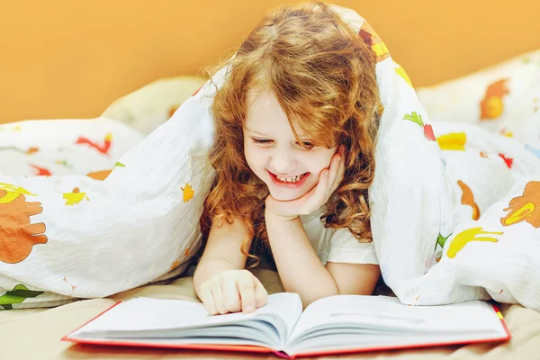 Маленькая девочка чтения книги в постели перед идти спать. Тонированный я — стоковое фото