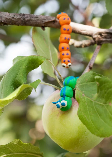 Пластилиновый мир - маленький домашний зеленый и оранжевый гусениц — стоковое фото