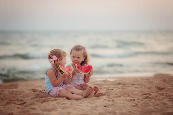 Девочки, есть спелый арбуз на пляже — стоковое фото
