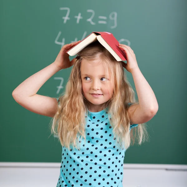 Девочка, уравновешивающая книгу по ее голове — стоковое фото