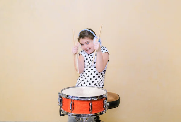 Радостная, очаровательная модная маленькая девочка в движении, сидящем позади барабана ловушки и держащемся палки в ее руках — стоковое фото