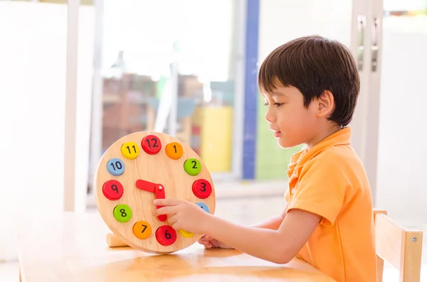 Маленький мальчик, изучающий время с игрушкой часов montessori educationa — стоковое фото