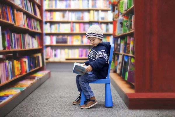 Прелестный маленький мальчик, сидя в книжном магазине — стоковое фото