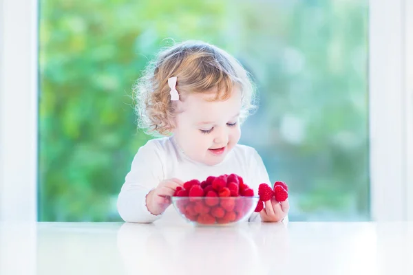 Милый малыш девочка ест малину в столовой с — стоковое фото