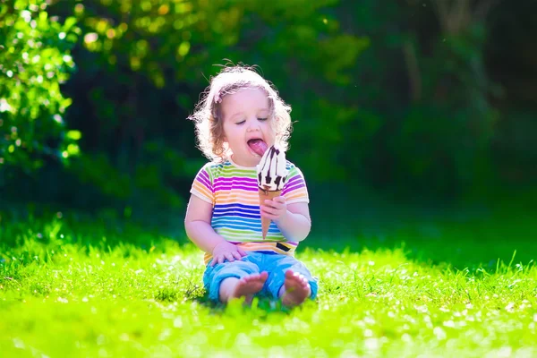Маленькая девочка ест мороженое в саду — стоковое фото