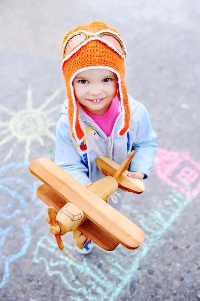 Девочка с деревянная игрушка самолет на фоне детей — стоковое фото