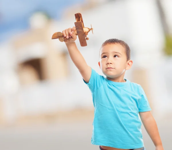Маленький мальчик, играющий с деревянным самолетом — стоковое фото