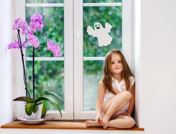 Милая маленькая девочка с цветком, сидя на подоконнике новой ПВХ wi — стоковое фото