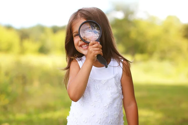Позитивные жизнерадостная девочка, глядя через увеличительное стекло — стоковое фото
