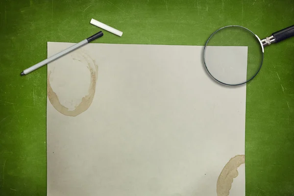 Зеленой доске с листа пустые бумаги и увеличительное стекло — стоковое фото