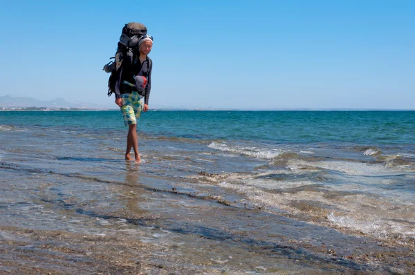 Турист с большой рюкзак, прогуливаясь по чистой водой Средиземного моря — стоковое фото