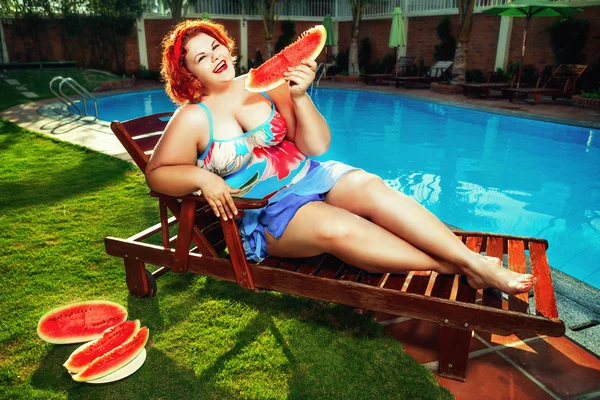 Избыточный вес женщины едят арбуз у бассейна — стоковое фото