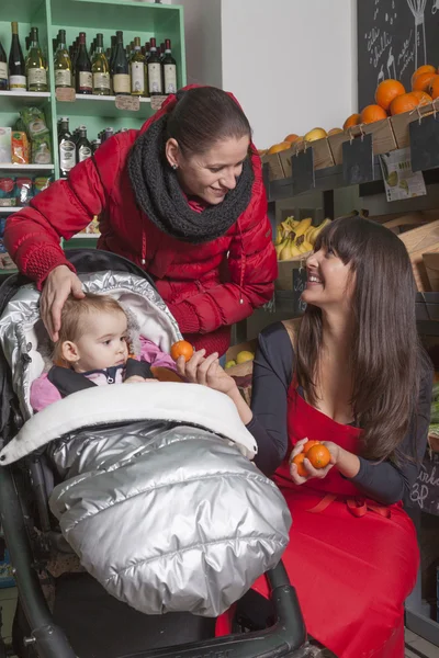 Мать малыша и магазин помощник на овощной — стоковое фото