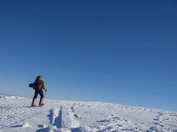 Альпинист проходит через снег, одетые в снегоступах — стоковое фото