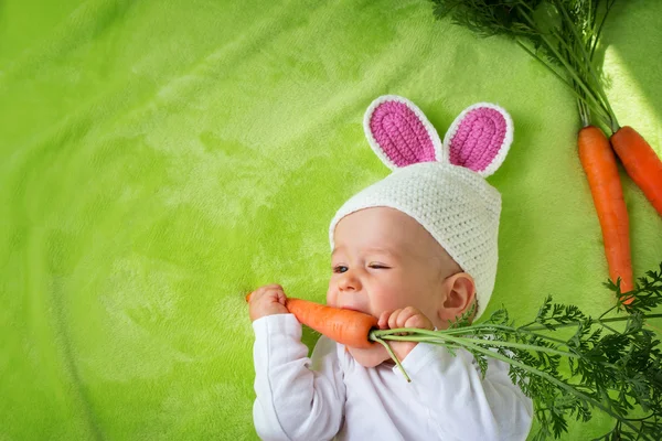 Ребенок в шляпе кролик ест морковь — стоковое фото