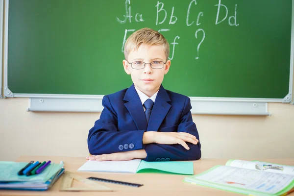 Школьник сидит за столом в школьном классе — стоковое фото