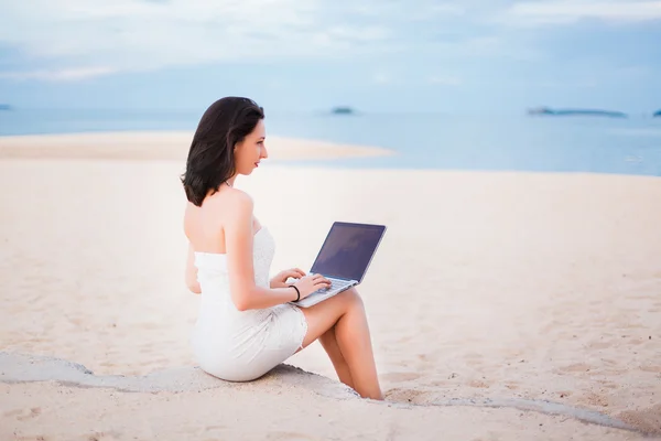 Девушка работает на ноутбуке на пляже — стоковое фото