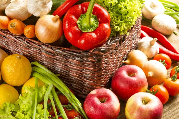 Плетеная корзина с фруктами и овощами на деревянный стол — стоковое фото