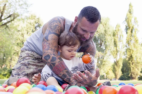 Татуированные отец весело провести время со своим сыном в парке с цветными b — стоковое фото