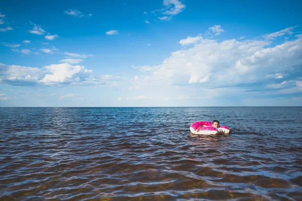 Мальчик-плавание на надувной пончик — стоковое фото