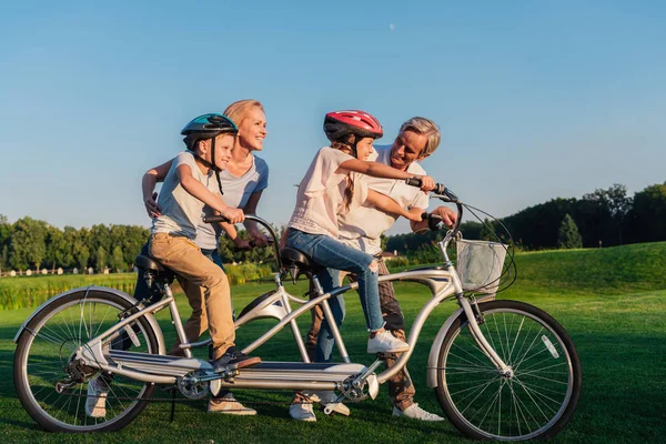 Бабушки и дедушки, помогая детям ездить на велосипеде — стоковое фото