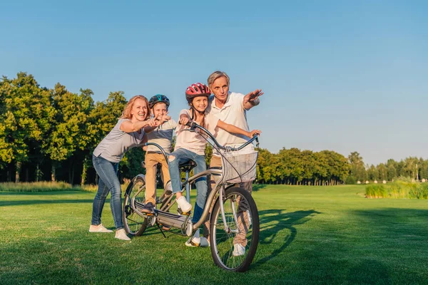 Бабушки и дедушки, помогая детям ездить на велосипеде — стоковое фото