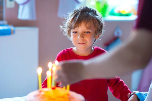 Маленький малыш мальчик празднует свой день рождения и дует свечи на торт — стоковое фото