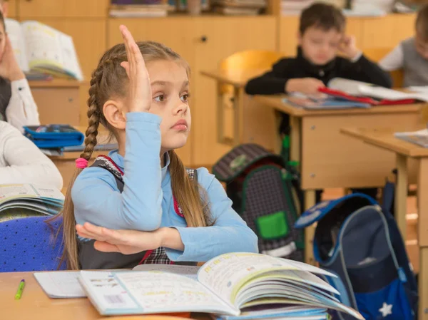 Девочка школьница на уроке в школе, желая тянуть руку до ответа вопрос — стоковое фото