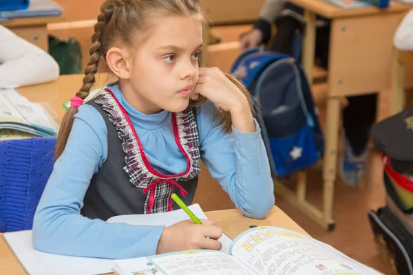 Девочка школьница сидит за столом в школе на уроке в школе — стоковое фото