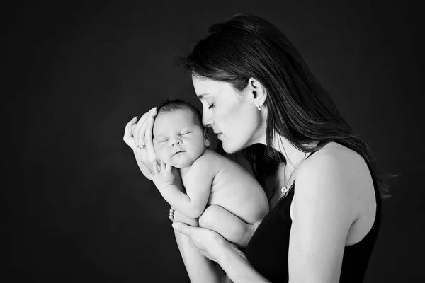 Мать целовать и обнимать новорожденного сына на сером фоне, тенд — стоковое фото
