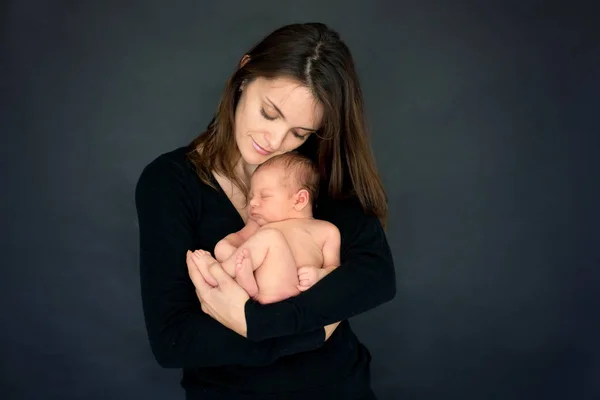 Мать целовать и обнимать новорожденного сына на сером фоне, тенд — стоковое фото