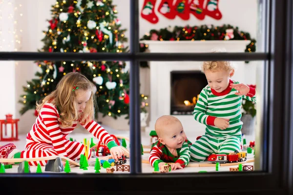 Дети, играя с игрушкой железной дороги на утро Рождества — стоковое фото