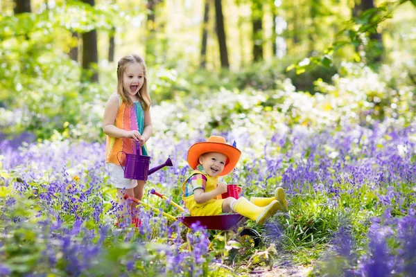 Дети с цветами колокольчика, садовый инвентарь — стоковое фото