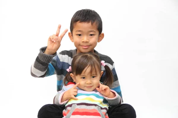 Japanese brother and sister sitting on his knee (7 years old boy and 2 years old girl) — стоковое фото