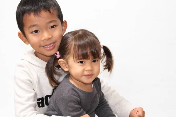 Japanese brother and sister sitting on his knee (7 years old boy and 2 years old girl) — стоковое фото