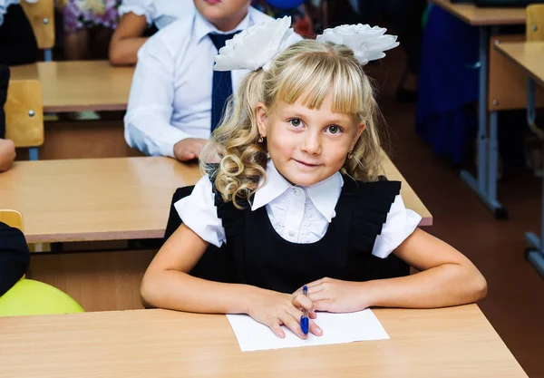 Девушка первый грейдер, сидя за партой на первый урок на 1 сентября — стоковое фото