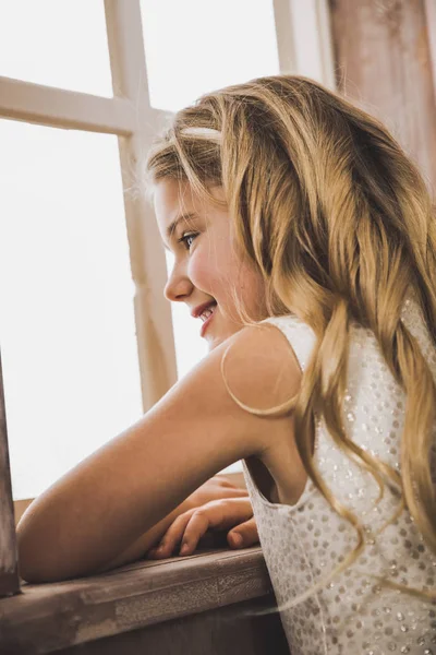 Симпатичная девушка смотрит в окно — стоковое фото