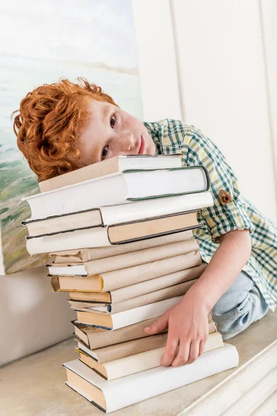 Маленький мальчик и куча книг — стоковое фото