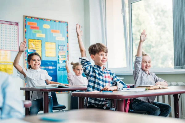 Дети, поднимая руки в классе — стоковое фото