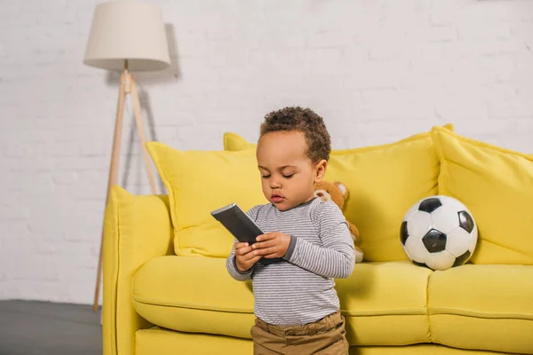 Adorable Little African American Child Holding Remote Controller Home — стоковое фото