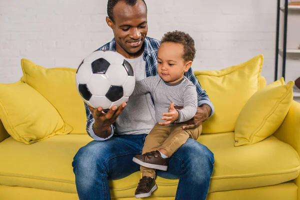 Happy Young Father Holding Soccer Ball While Sitting Adorable Little — стоковое фото